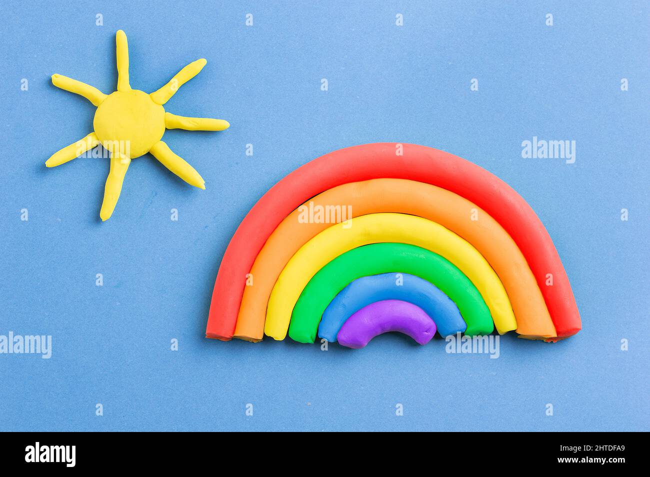Arcobaleno di plastilina e sole su sfondo blu Foto Stock