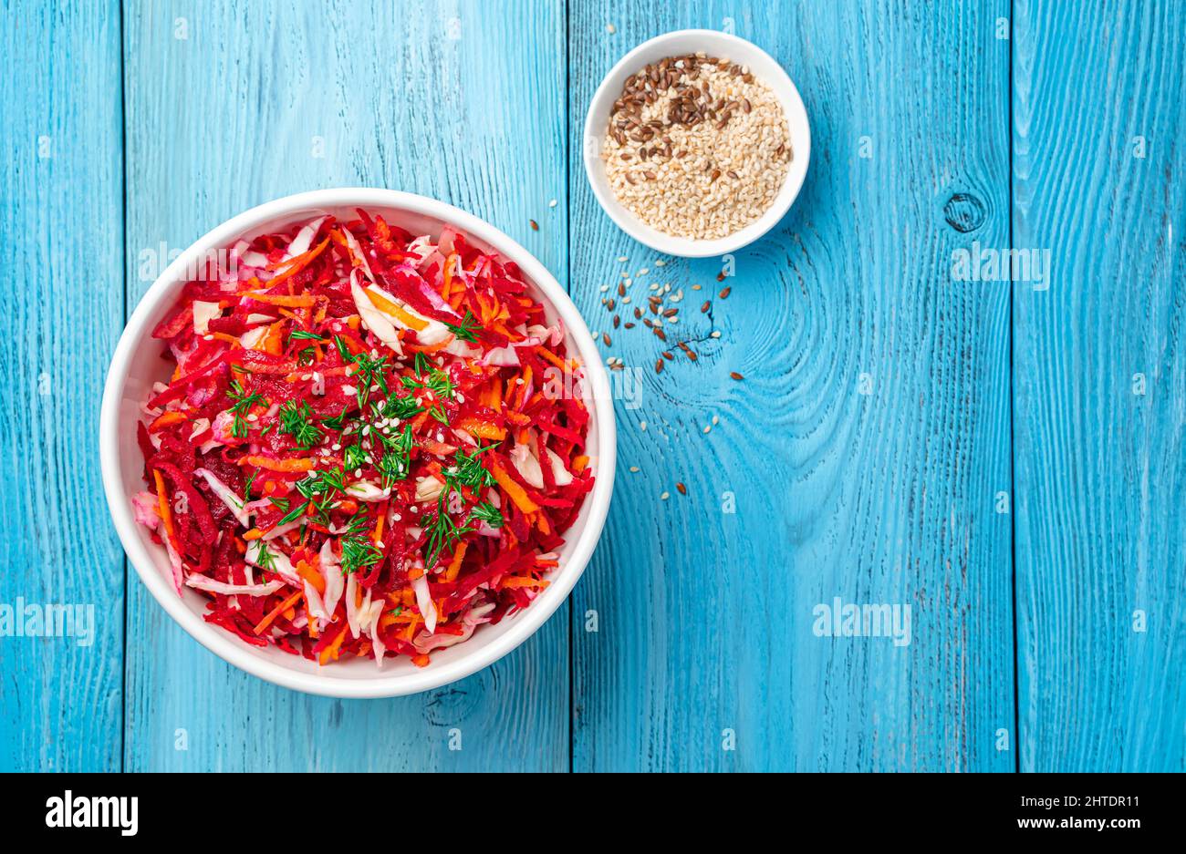 Insalata con verdure fresche su sfondo blu con semi di sesamo. Foto Stock