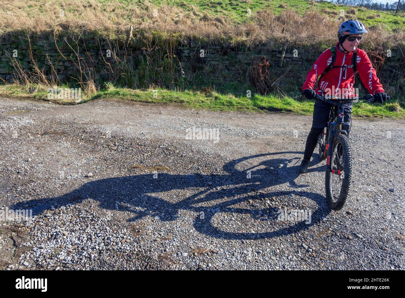 Il ciclista del biker offroad prende un breater che getta una lunga ombra nel sole di pomeriggio. Foto Stock