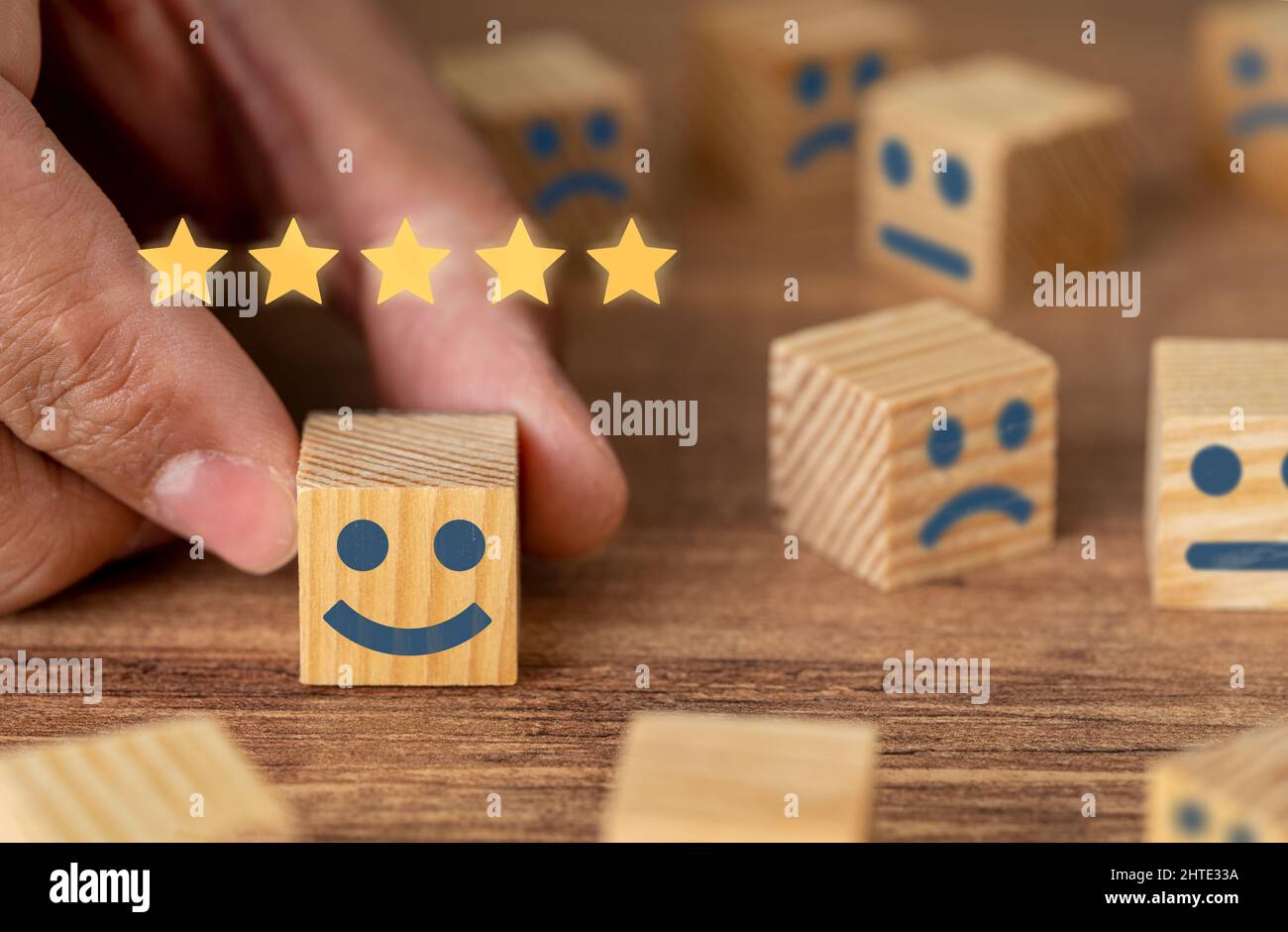 Raccolta a mano sorridente fronte cubo di legno e 5 stelle. Simbolo di revisione e valutazione del servizio clienti. Feedback sulla soddisfazione del cliente, sondaggio. Foto Stock