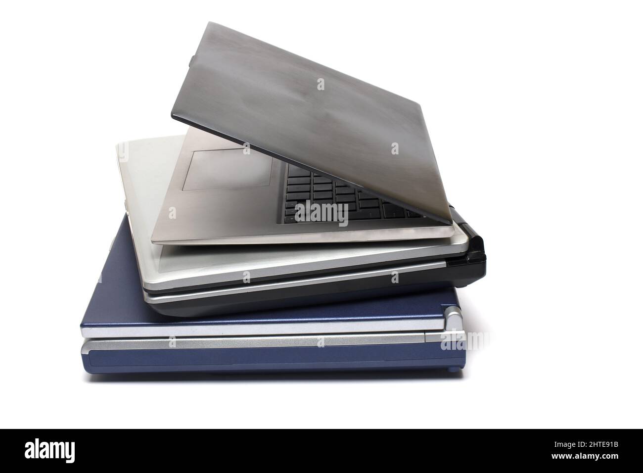 Primo piano di tre notebook impilati di diverse generazioni, da vecchi e pesanti a moderni e ultraleggeri su sfondo bianco Foto Stock