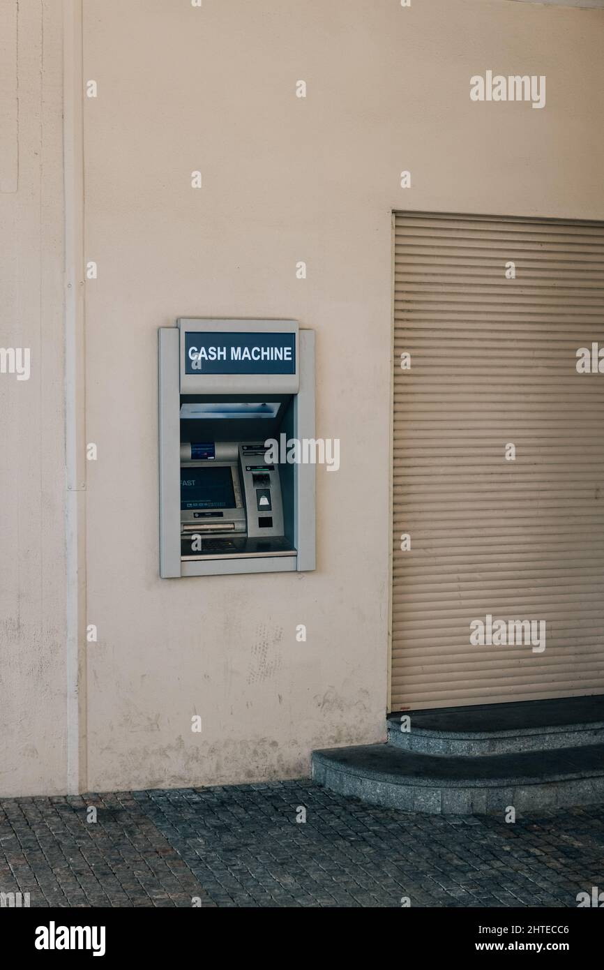 Colpo verticale di una macchina ATM sul blocco bianco della parete Foto Stock