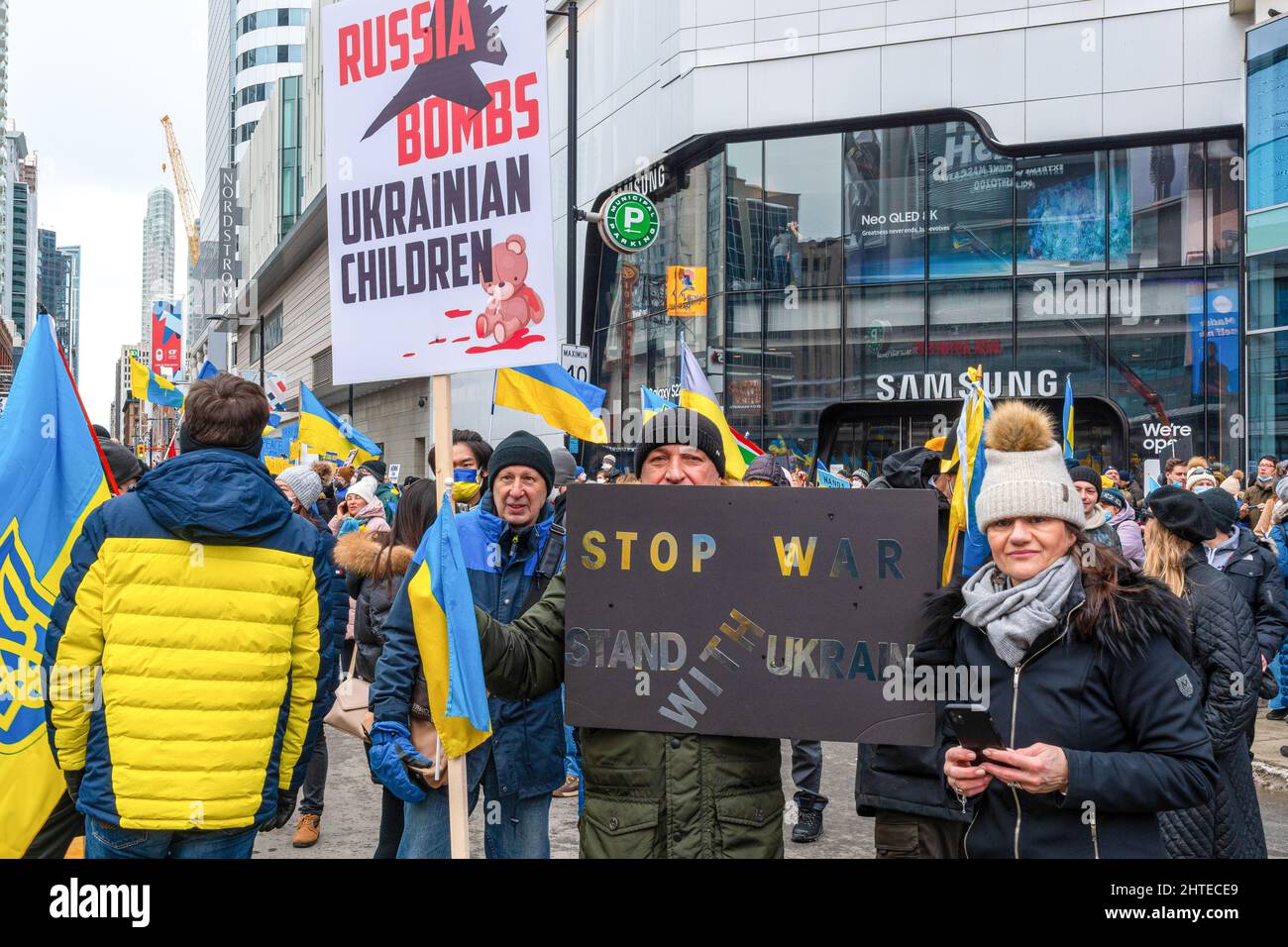 Toronto, Canada - 27 febbraio 2022: Le persone che partecipano alla manifestazione con i segni che leggono ' Russia bombe Bambini ucraini' e 'Stop the War'. Foto Stock