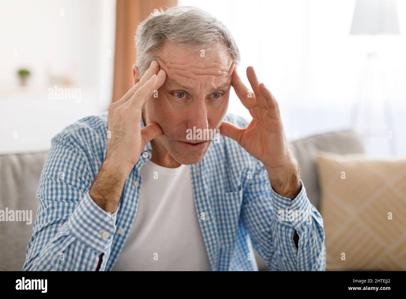 Stressato uomo maturo seduto sul divano e pensando Foto Stock
