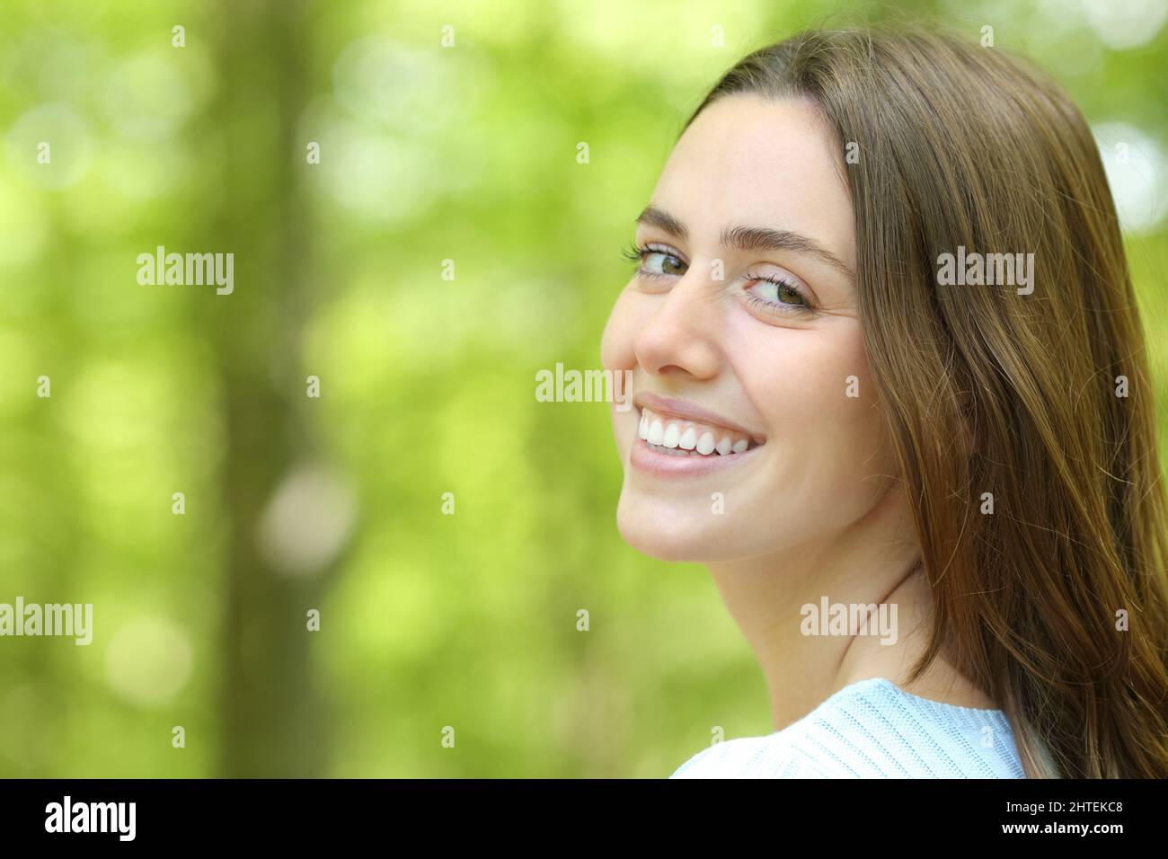 Bella donna con un bel sorriso guardando la macchina fotografica in un parco verde Foto Stock