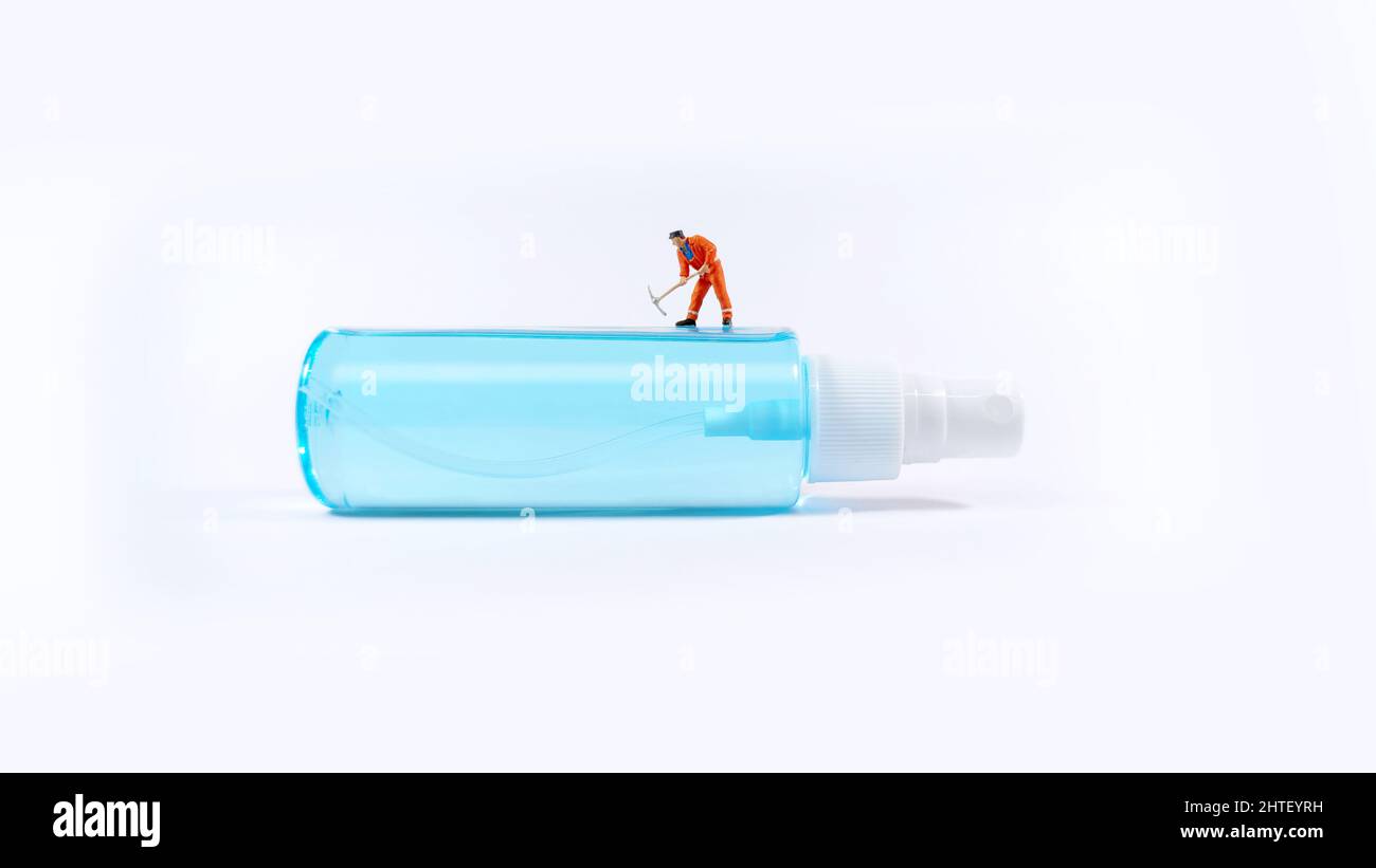 Figura del tecnico che lavora in piedi su una bottiglia di alcool spray. Concetto di Covid-19. Foto Stock