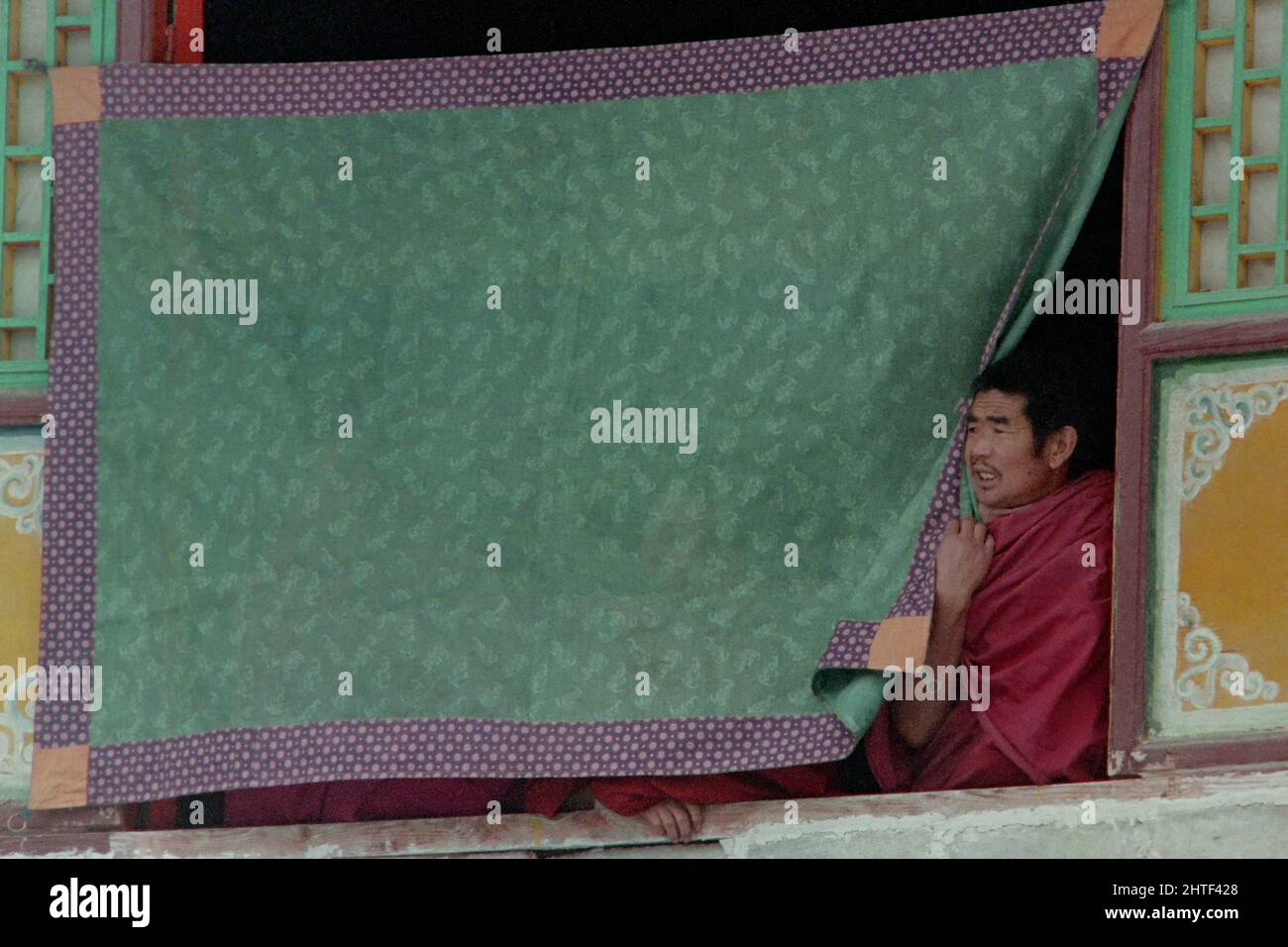 I monaci buddisti tibetani osservano la danza Cham dall'esterno della finestra durante le celebrazioni del Monlam che segnano il nuovo anno tibetano al monastero di Kumbum, noto anche come monastero Ta'er, 12 febbraio 1990 a Lusar, Xining, Qinghai, Cina. Foto Stock