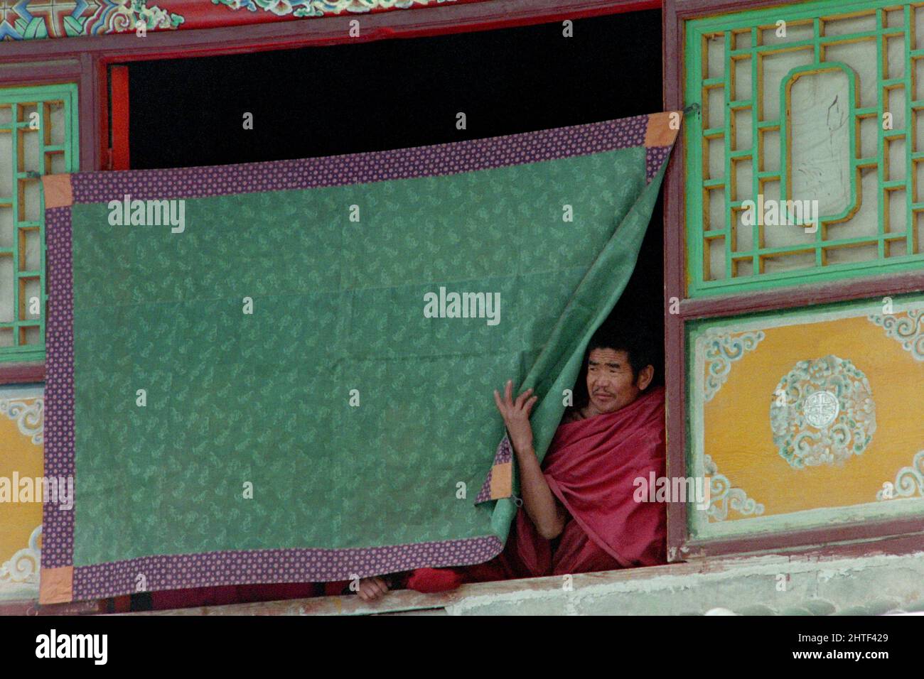 I monaci buddisti tibetani osservano la danza Cham dall'esterno della finestra durante le celebrazioni del Monlam che segnano il nuovo anno tibetano al monastero di Kumbum, noto anche come monastero Ta'er, 12 febbraio 1990 a Lusar, Xining, Qinghai, Cina. Foto Stock