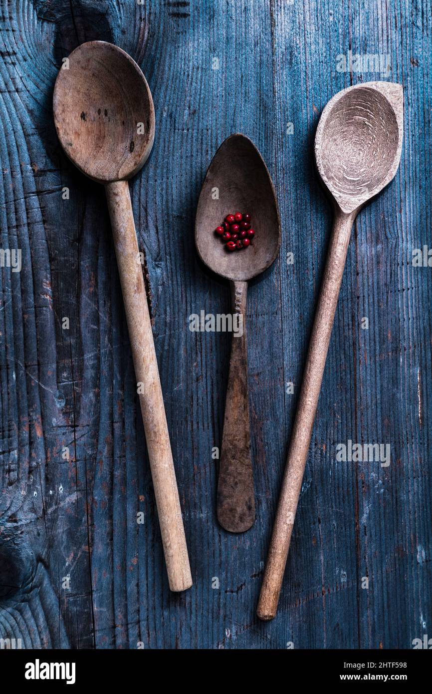 vecchi cucchiai di legno con grani di pepe su un rustico sfondo di legno Foto Stock