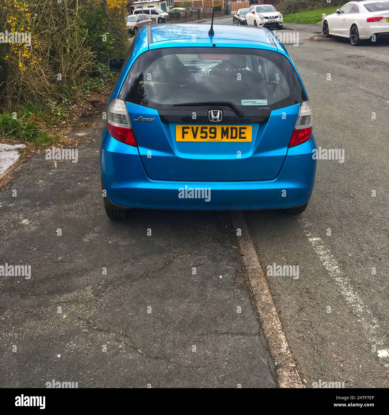 L'auto è stata parcheggiata completamente sul marciapiede e costringe i pedoni e i bambini a camminare su una strada trafficata Foto Stock