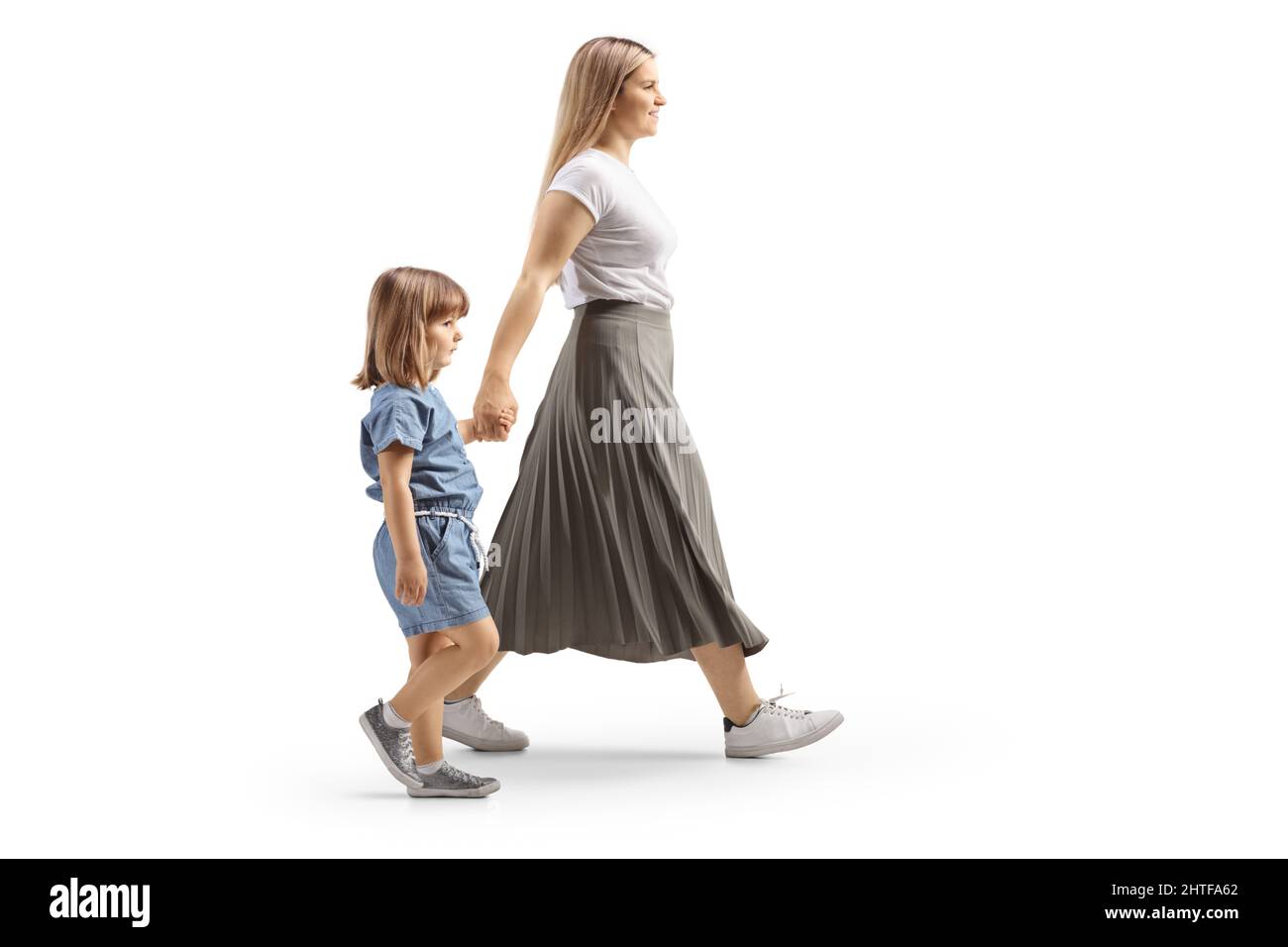 Ripresa a tutto profilo di una madre e figlia che camminano tenendo le mani isolate su sfondo bianco Foto Stock