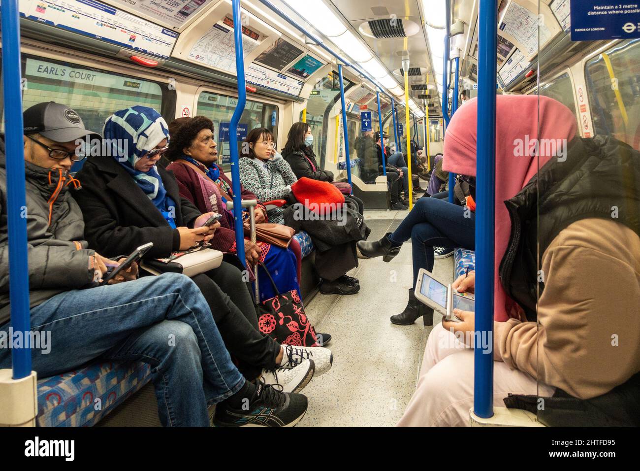 Passeggeri su un treno Piccadilly Line della metropolitana di Londra. Il treno è occupato ma tutti hanno un posto a sedere. Foto Stock