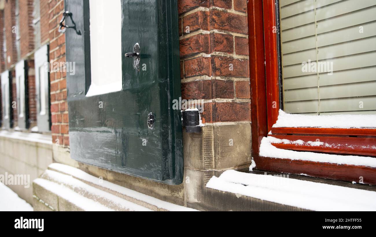 Finestra con persiane su un antico edificio della provincia di Groningen con qualche neve in inverno Foto Stock