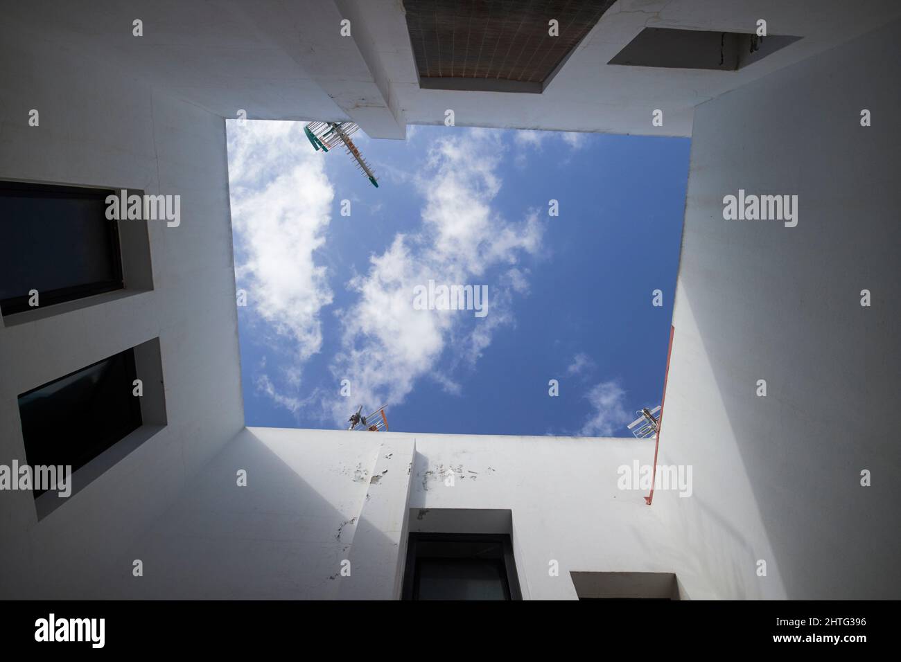 Guardando in su al cielo nuvoloso blu dal cortile interno centrale del blocco di appartamenti Lanzarote, isole canarie, spagna Foto Stock