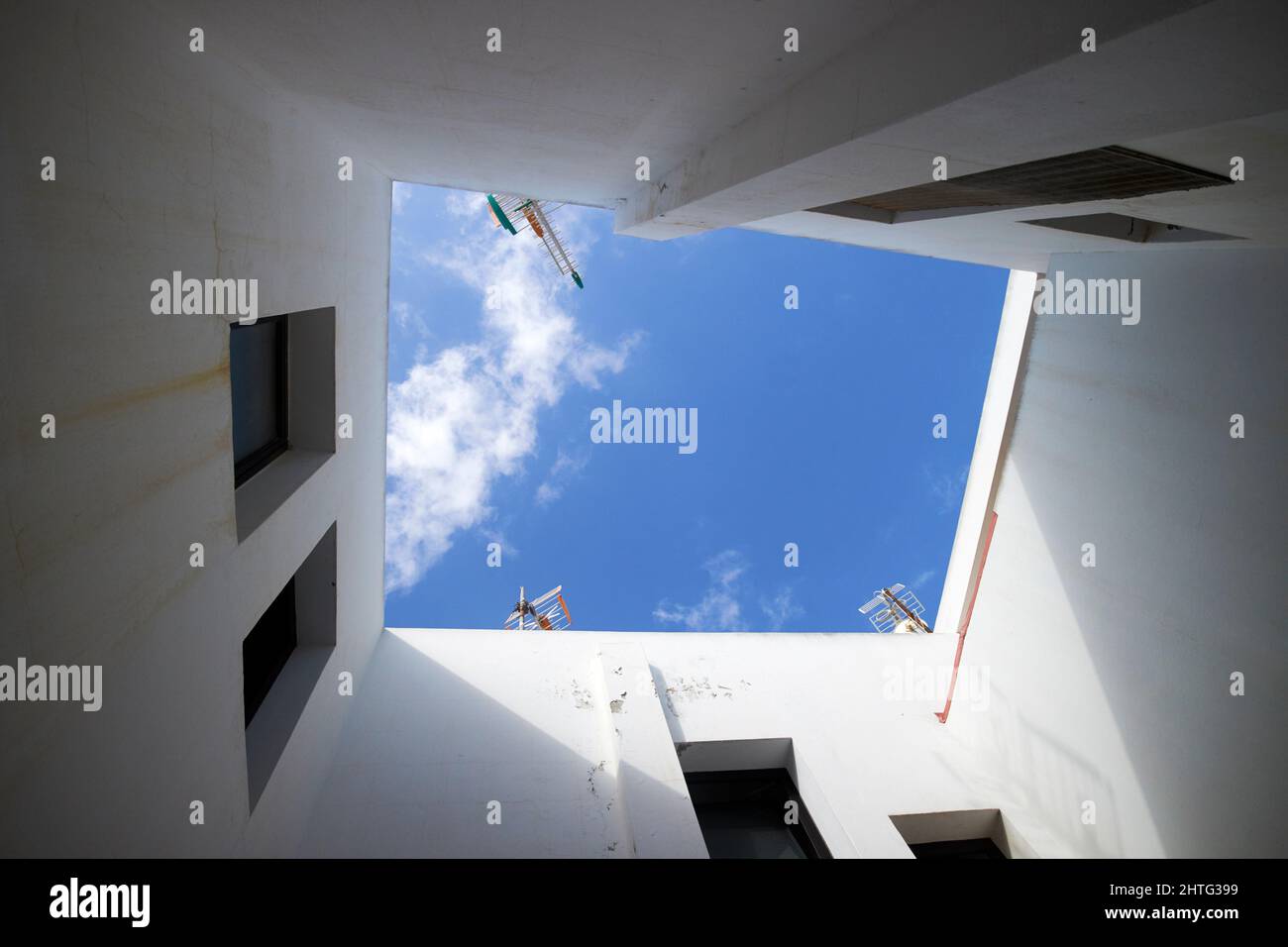 Guardando in su al cielo nuvoloso blu dal cortile interno centrale del blocco di appartamenti Lanzarote, isole canarie, spagna Foto Stock
