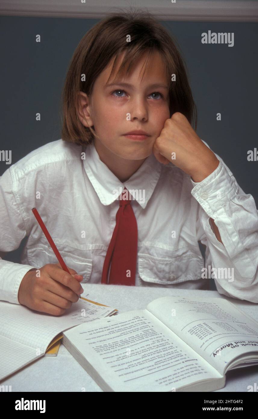 giovane ragazza in uniforme che lotta sopra i compiti di matematica Foto Stock