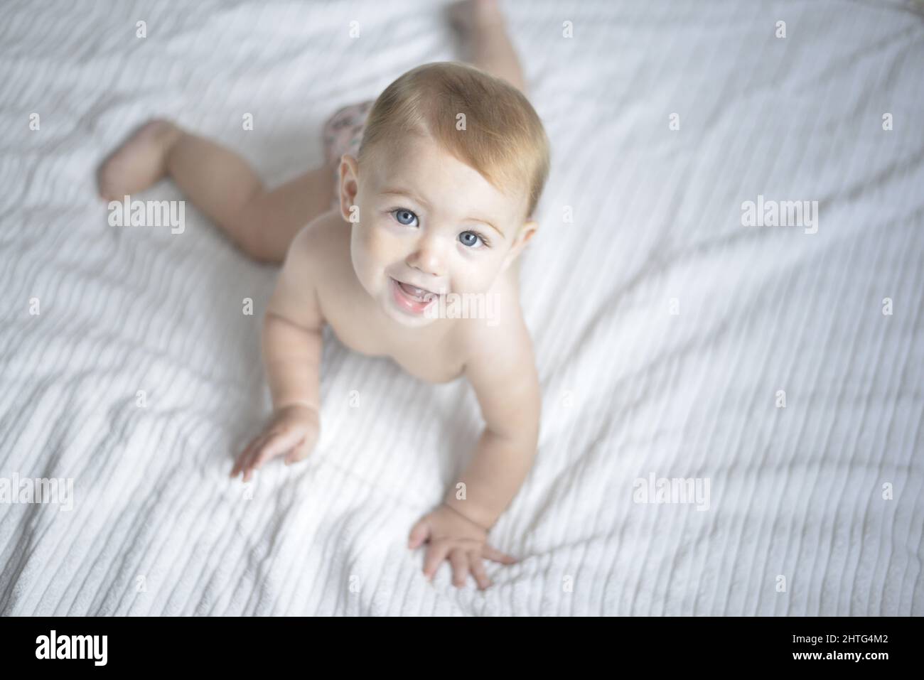 Scatto ad angolo alto di un bambino sorridente sul letto Foto Stock