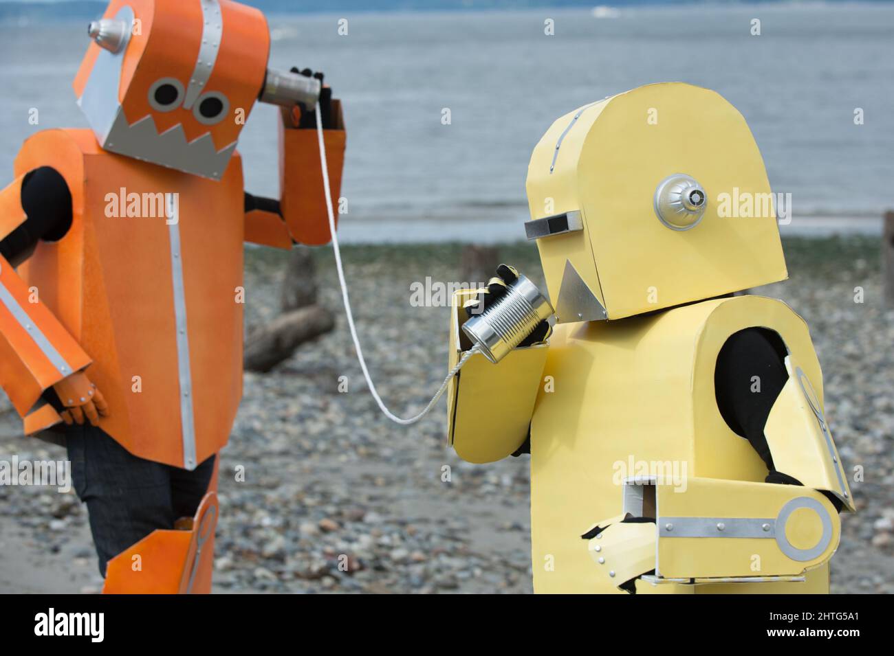 Due robot colorati che comunicano, conversando tra loro attraverso il telefono in lattina. Comunicazione CAN TIN. I robot parlano. Foto Stock