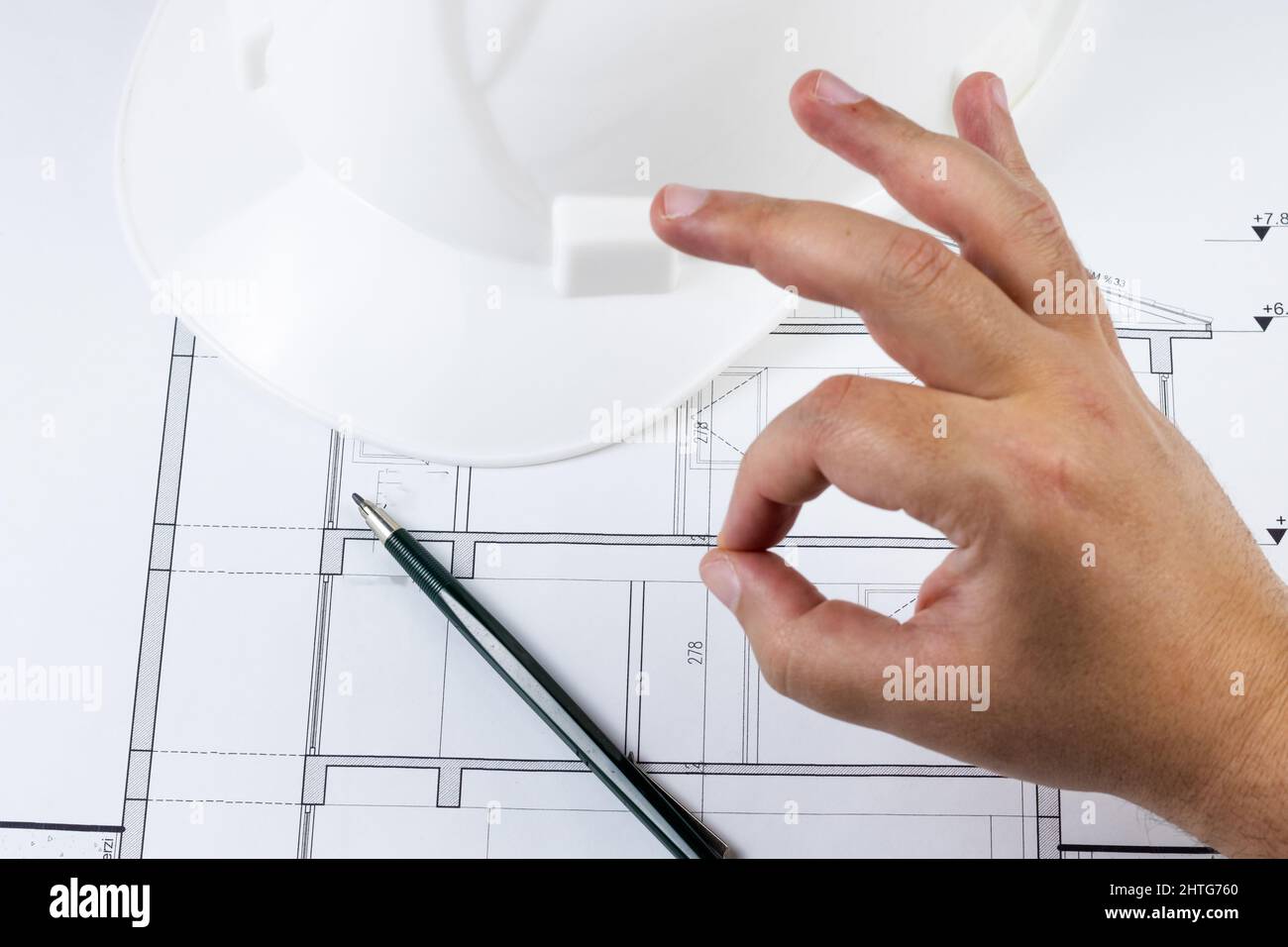 L'uomo come il progetto o il piano architettonico o il business con mostrare italiano come gesto. Progetto con matita e casco sullo sfondo. Foto Stock