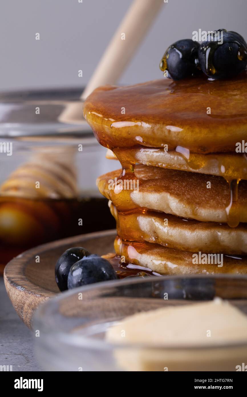 Primo piano del miele che gocciola sulle frittelle accatastate nel piatto Foto Stock