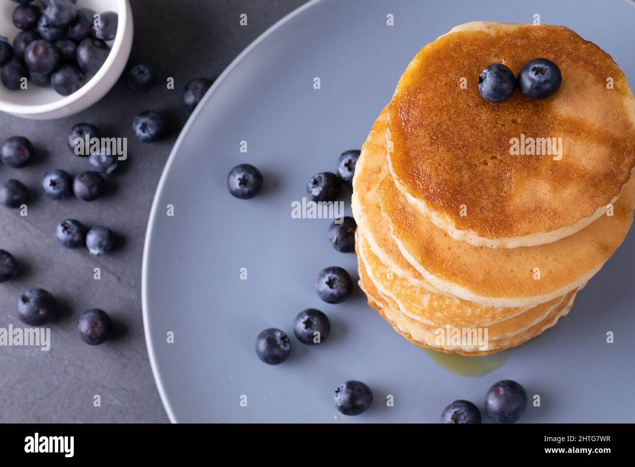 Direttamente sopra la dose di pancake impilati con bacche blu e sciroppo nel piatto sul tavolo Foto Stock