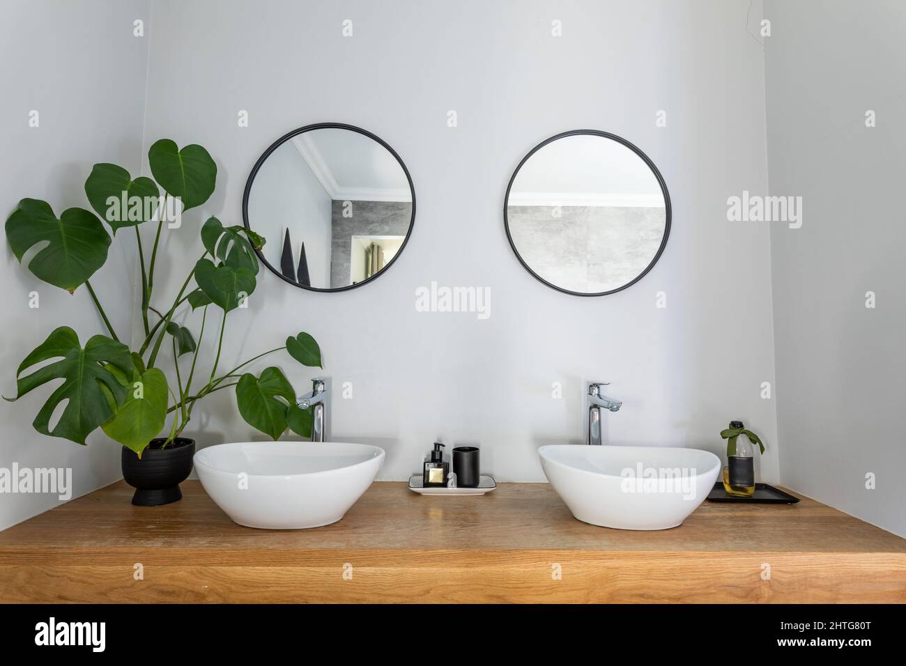 Specchi di forma circolare montati sulla parete sotto i lavandini nella stanza da bagno in casa Foto Stock