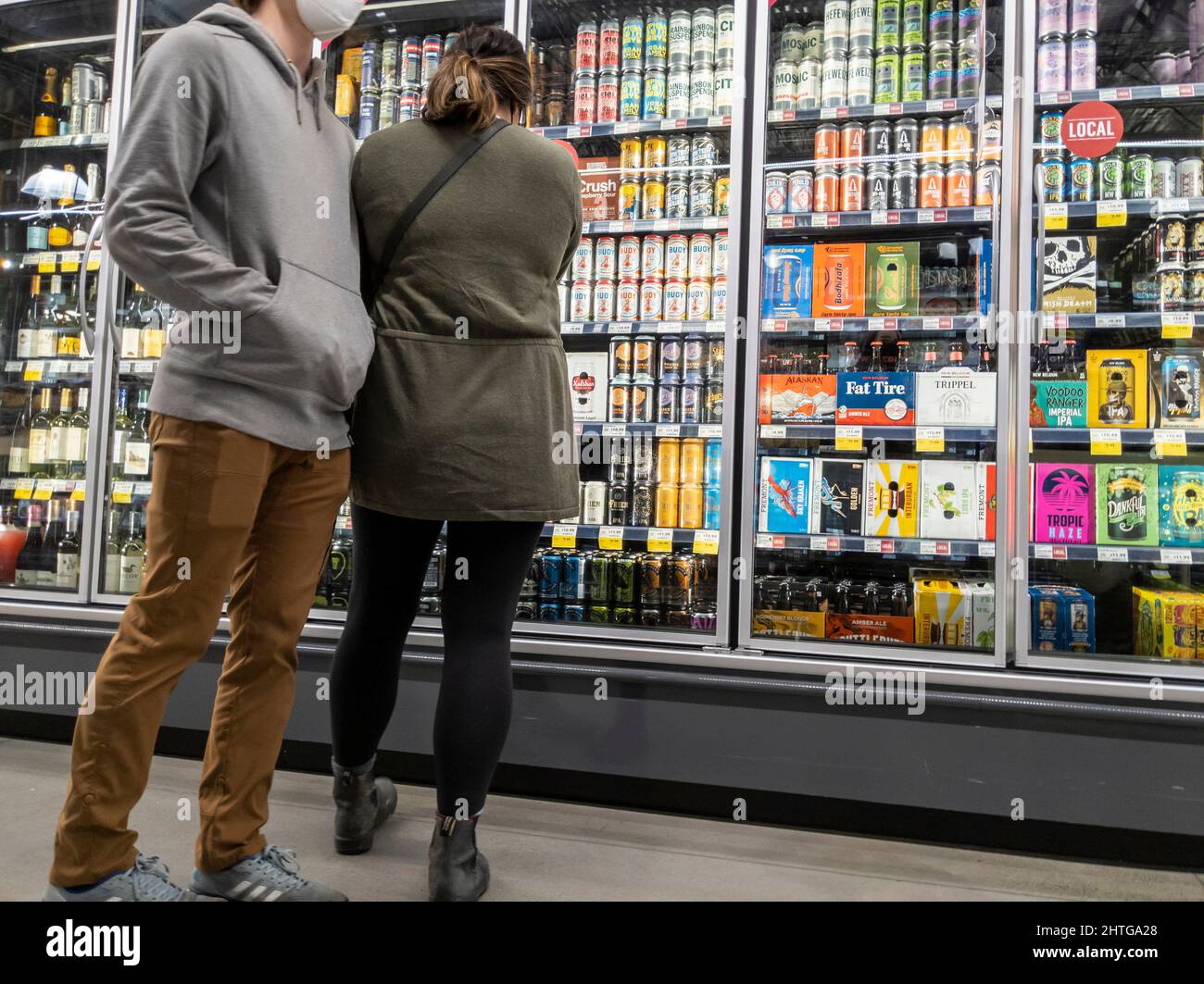 Kirkland, WA USA - circa Febbraio 2022: Un uomo caucasico e una donna asiatica che acquista birra nella sezione alcol di un intero mercato alimentare. Foto Stock Kirkland, WA USA - circa Febbraio 2022: Un uomo caucasico e una donna asiatica che acquista birra nella sezione alcol di un intero mercato alimentare. Foto Stock