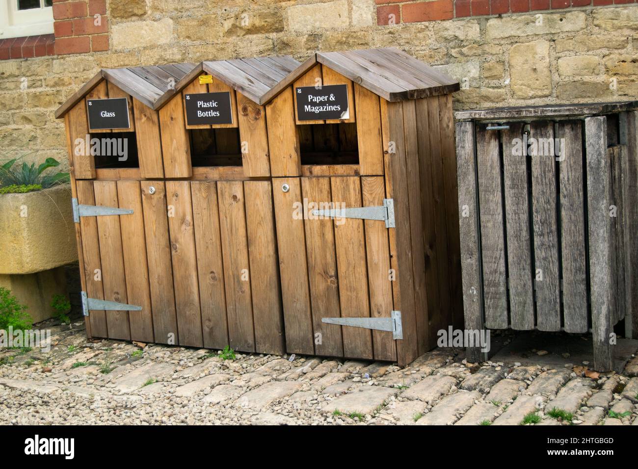 Tre bidoni di riciclaggio in legno con accanto un bidone per rifiuti non riciclabili. Carta, riviste, bottiglie di vetro e plastica riciclano le unità accanto al Foto Stock