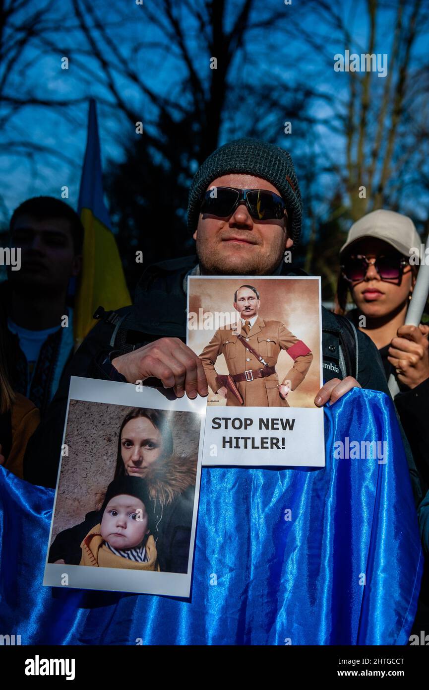 L'Aia, Paesi Bassi. 28th Feb 2022. Un manifestante tiene un cartello con l'immagine di Putin come Hitler durante una manifestazione contro l'invasione russa dell'Ucraina e del presidente russo, Putin.la comunità Ucraina nei Paesi Bassi si riunisce per protestare contro Putin e la guerra in Ucraina lo stesso giorno in cui il parlamento olandese sta discutendo dell'invasione russa dell'Ucraina, al di fuori dell'edificio della Camera dei rappresentanti. Il popolo ucraino chiede al governo olandese aiuto per fermare Putin e il suo esercito. (Foto di Ana Fernandez/SOPA Images/Sipa USA) Credit: Sipa USA/Alamy Live News Foto Stock