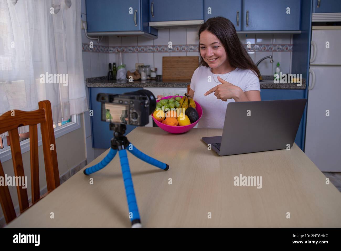 Un influencer in casa si film la creazione di un video per il suo sito web, con il tema della nutrizione e cibo sano, il creatore di contenuti punti a un frutto Foto Stock