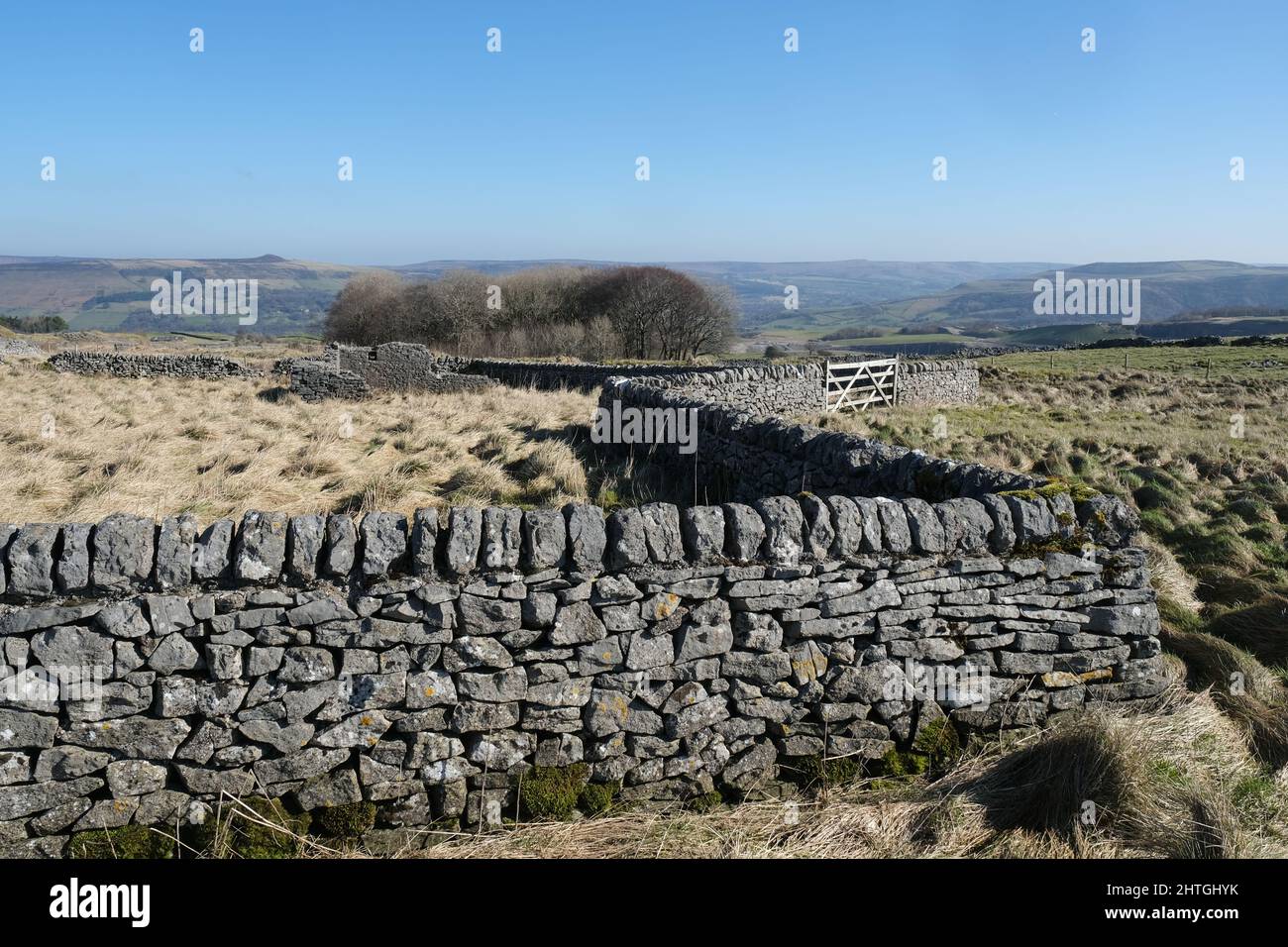 Pareti in pietra calcarea circondano un edificio abbandonato e derelitto fattoria vicino Castleton con le dolci colline del Derbyshire sullo sfondo. Foto Stock