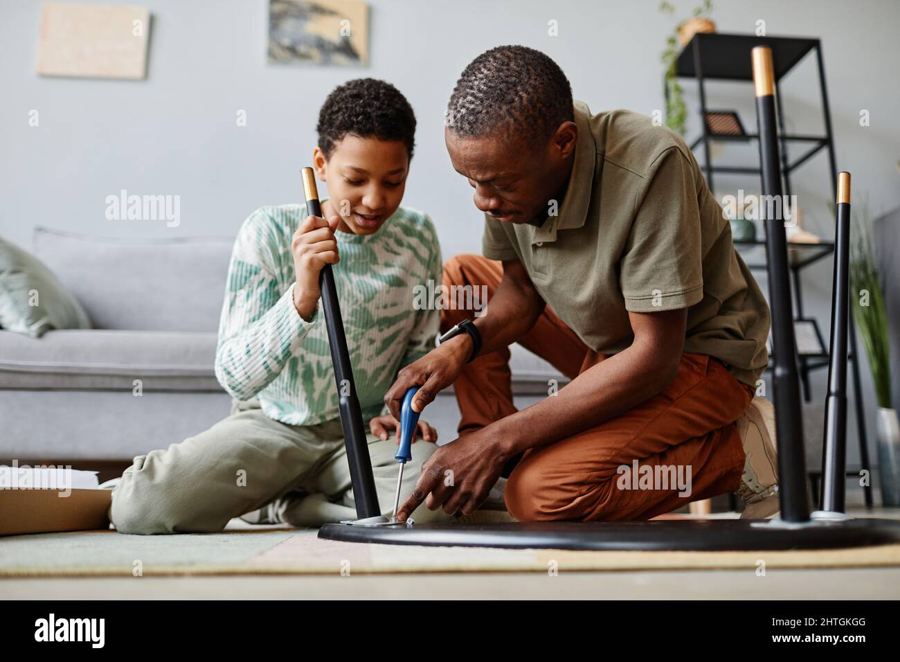 Ritratto di uomo afroamericano che monta i mobili a casa con la figlia aiutare Foto Stock