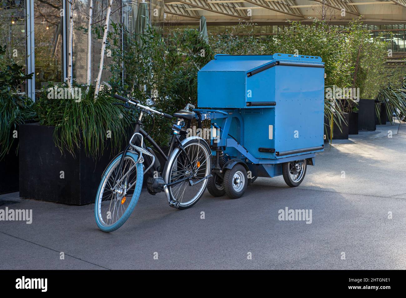 Una bici da carico parcheggiata su una strada della città di fronte agli alberi Foto Stock