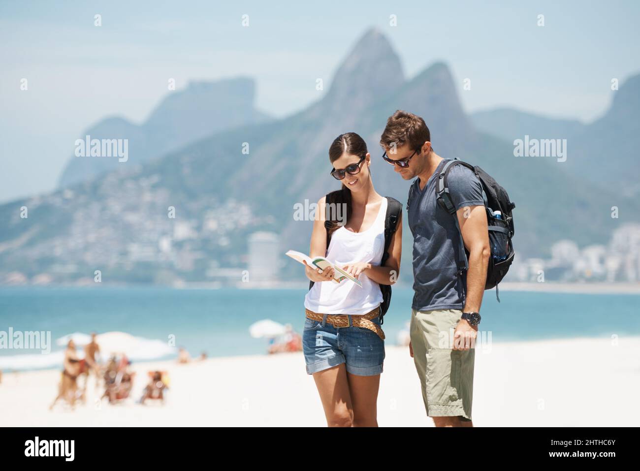 Ottenere i nostri cuscinetti in paradiso. Scatto di una giovane coppia che guarda una mappa mentre si trova su una spiaggia. Foto Stock