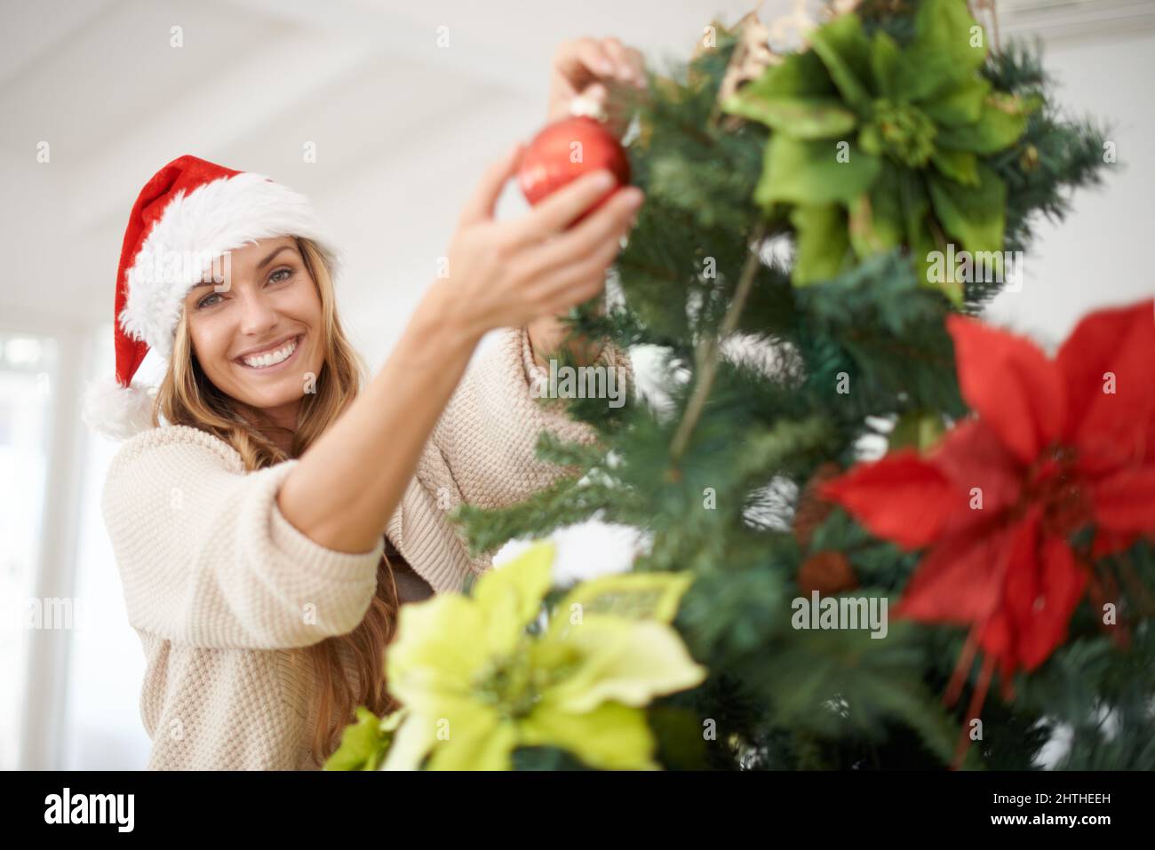 La mia parte preferita della vacanza. Una donna attraente che decora il suo albero di natale mentre a casa. Foto Stock
