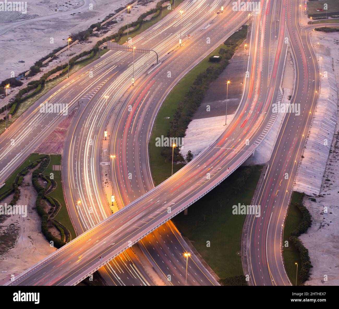 Vista aerea di una strada a più livelli che attraversa l'ora di sera con sentieri di semafori. Foto Stock