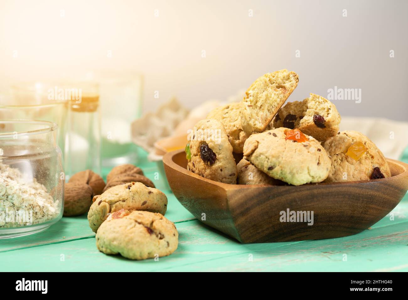 Biscotti di farinata d'avena appena sfornati con uvetta, frutta candita, semi di lino e sesamo e noci da vicino in un piatto di legno a forma di cuore Foto Stock