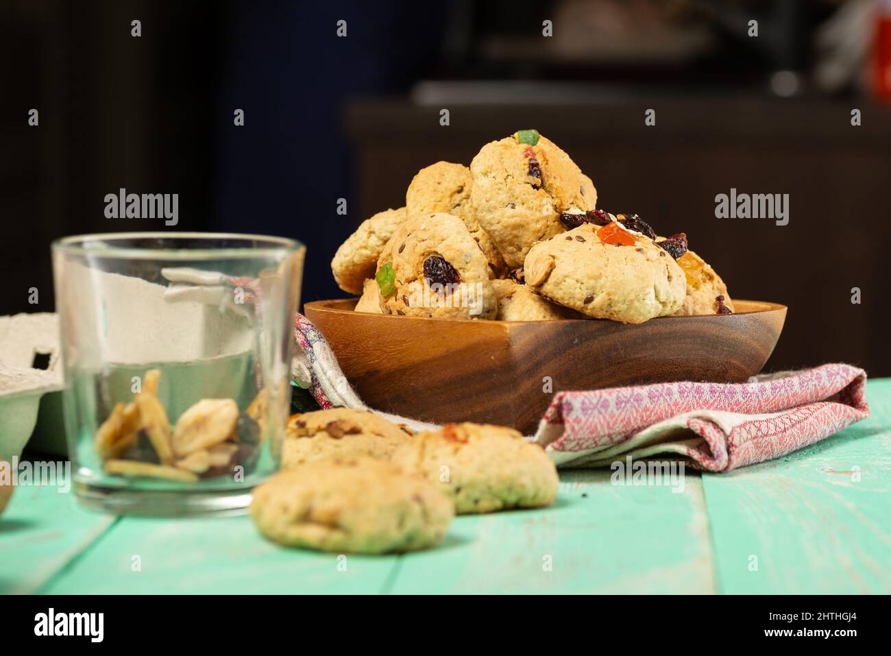 Biscotti di farinata d'avena appena sfornati con uvetta, frutta candita, semi di lino e sesamo e noci da vicino in un piatto di legno Foto Stock