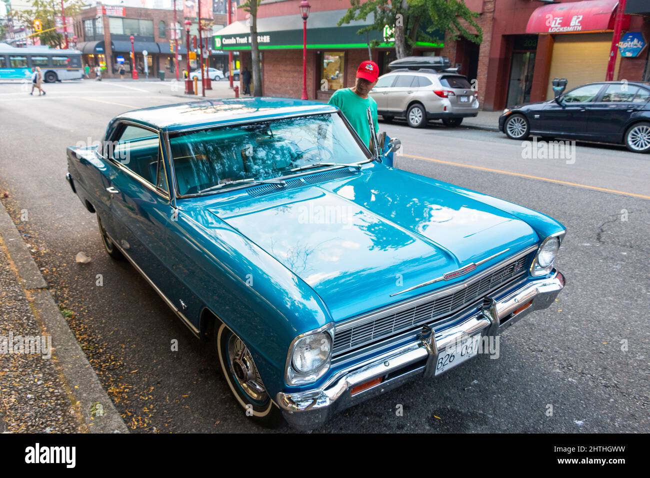 L'uomo entra nel blu d'epoca 1960s Chevrolet nova in una strada a Vancouver Canada Foto Stock