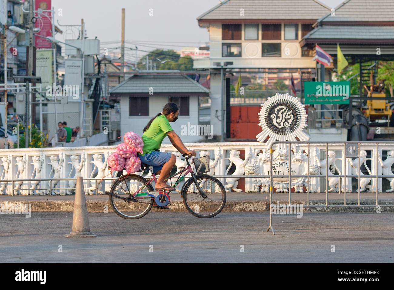 Un ciclista con un carico di cipolle da un vicino mercato che passa sopra il ponte Charoenrat 31, un ponte klong (canale) a Bangkok, Thailandia Foto Stock