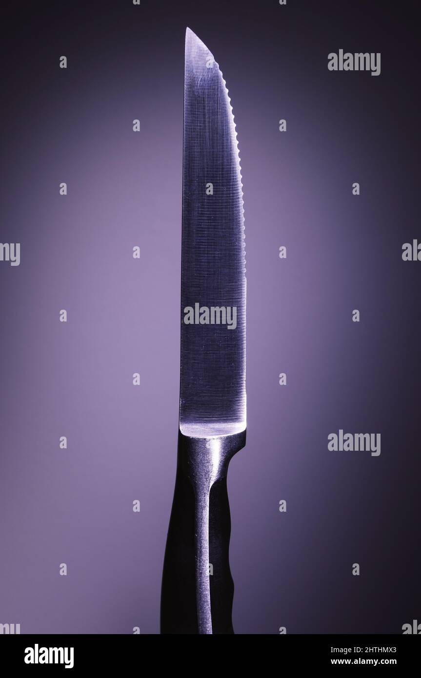 Primo piano di un coltello in metallo su sfondo viola, approccio minimalista, composizione studio. Foto Stock