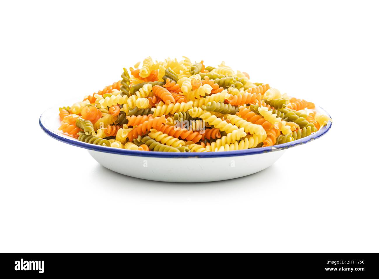 Fusilli in ciotola a tre colori. Pasta cruda italiana colorata isolata su sfondo bianco. Foto Stock
