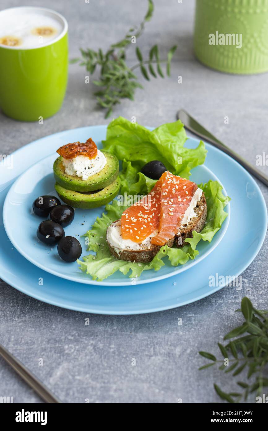 Colazione sana. Sandwich con salmone affumicato, avocado su foglie di insalata di lattuga e caffè Foto Stock