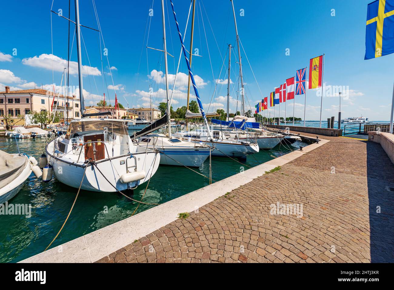 Barche a vela e barche da diporto ormeggiate nel piccolo porto del villaggio di Bardolino. Località turistica, costa del Lago di Garda. Verona, Veneto, Italia, Europa. Foto Stock