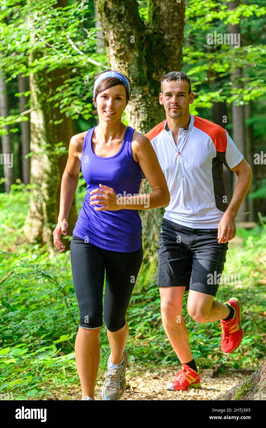 Coppia giovane jogging nella foresta - faticoso allenamento in estate Foto Stock