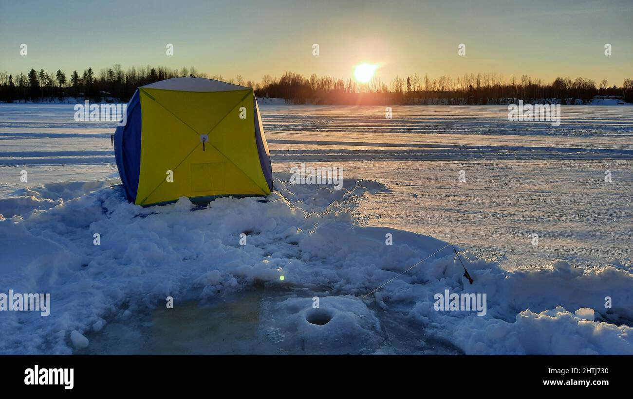 pesca invernale. Pesce con canna e buco in ghiaccio sullo sfondo in Svezia Foto Stock