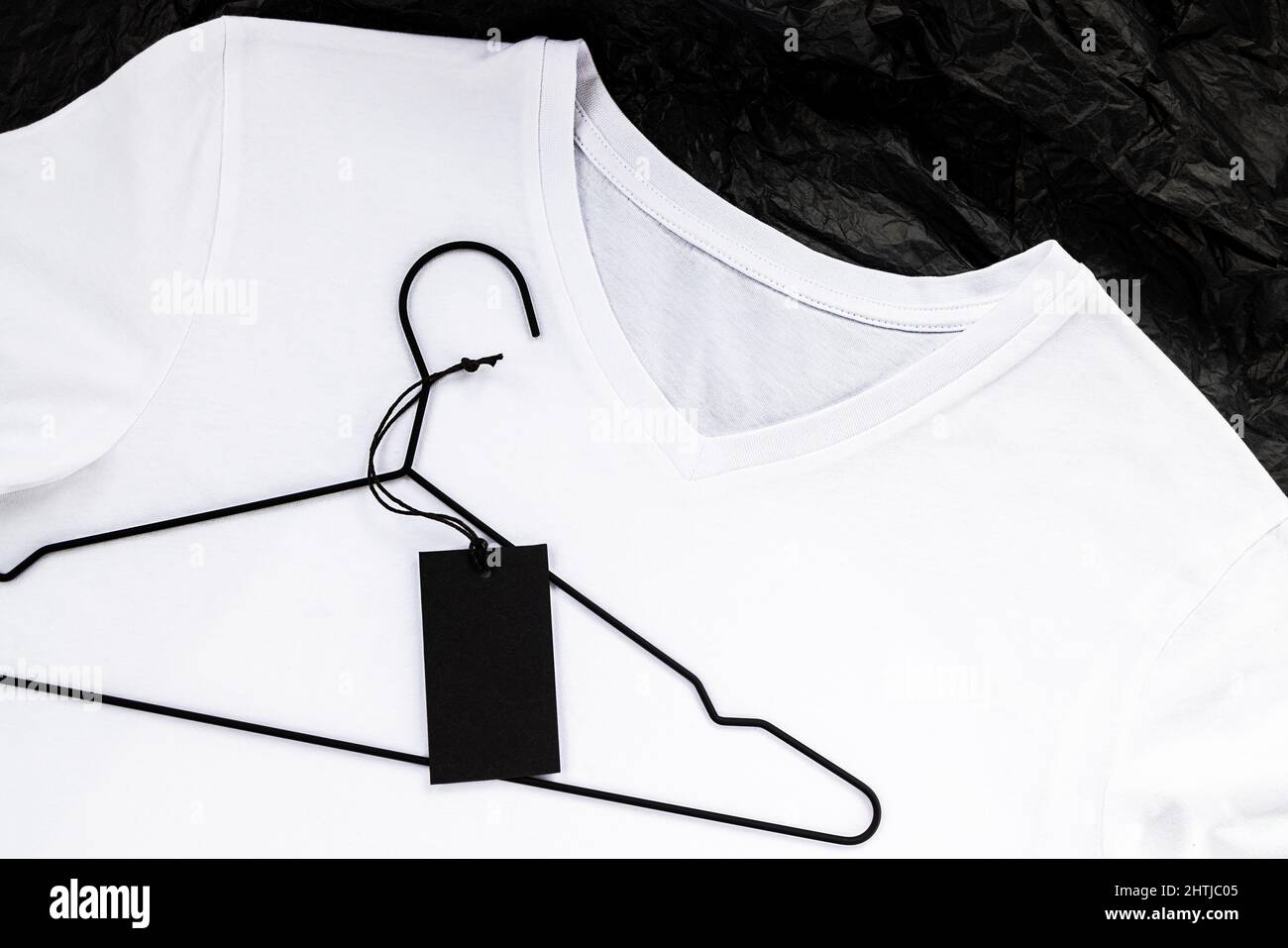 Mockup t-shirt in cotone bianco. Posizionare un logo o un'etichetta, primo piano. Etichetta nera su un gancio. Foto Stock
