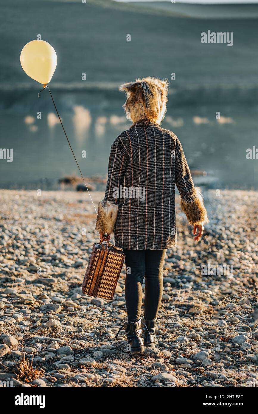 Da sotto di sorridente signora adulta in abiti casual in piedi vicino recinto e vecchio edificio, mentre navigando al telefono nel quartiere della città in luce del giorno Foto Stock