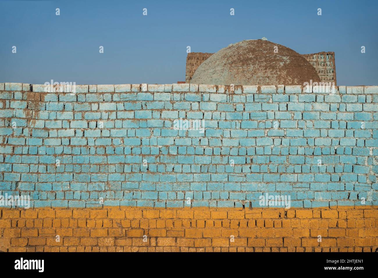 Ruvido tempo colorato muro di mattoni dipinti situato sulla strada della città con vecchio edificio contro cielo blu nuvoloso in Egitto Foto Stock