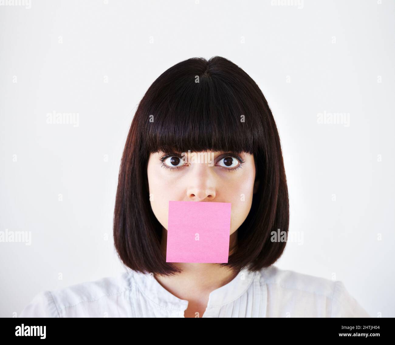 Lo stress soffoca la sua voce creativa. Immagine concettuale di una giovane donna d'affari con una nota rosa post-it che copre la sua bocca. Foto Stock